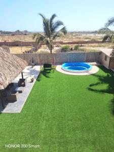 ein Hinterhof mit grünem Rasen und Pool in der Unterkunft Maderobeach1 in Máncora