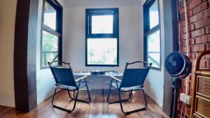 two chairs and a table in a room with windows at Samwise Escapade Hillside Guesthouse - Master Room in Kampong Perlis