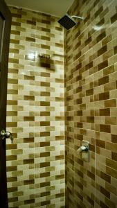 a bathroom with a shower with a tiled wall at Samwise Escapade Hillside Guesthouse - Master Room in Kampong Perlis