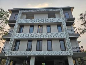 a tall white building with a balcony at Babus Serviced Apartments in Coimbatore