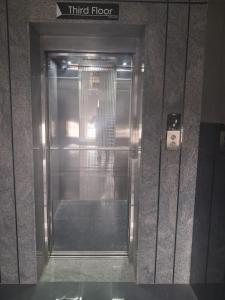 a metal elevator in a building with a person in it at Babus Serviced Apartments in Coimbatore