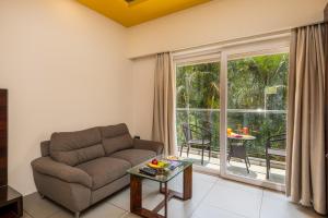 a living room with a couch and a large window at Regenta Central North Goa, Arpora in Arpora