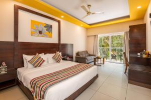 a bedroom with a large bed and a living room at Regenta Central North Goa, Arpora in Arpora