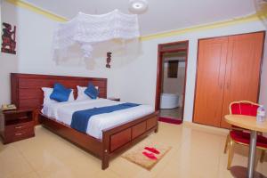 ein Schlafzimmer mit einem Bett mit blauen Kissen und einem Tisch in der Unterkunft FortBreeze Hotel in Fort Portal