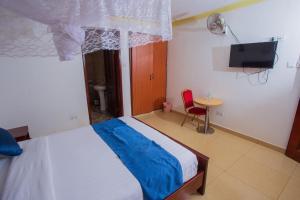 ein Schlafzimmer mit Bett, Fernseher und Tisch in der Unterkunft FortBreeze Hotel in Fort Portal