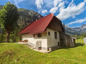 a small building with a red roof on a green field at Idina domačija in Trenta