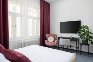 a bedroom with a bed and a tv and a chair at Hotel Botanica by goodnite cz in Brno