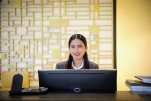 Eine Frau sitzt an einem Schreibtisch mit einem Laptop. in der Unterkunft Century Hotel Doha in Doha