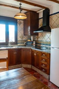 a kitchen with wooden cabinets and a white refrigerator at Cortijo La Presa in Priego de Córdoba