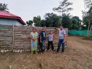 a family standing in front of a wooden fence at Himjoy farm in Dādo Sība