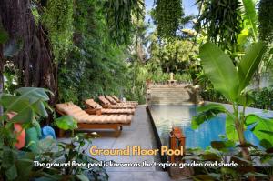 a pool with a bunch of lounge chairs in a garden at The Community - Siem Reap in Siem Reap