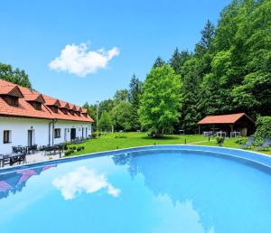 a large swimming pool in front of a house with trees at Penzion Na bezu in Drahonice