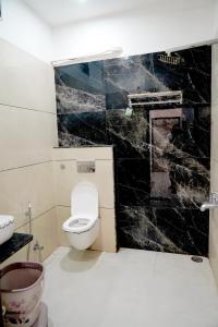 a bathroom with a toilet and a black marble wall at Hotel Shree Karni Palace in Deshnoke