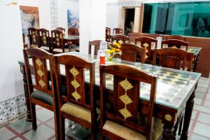 a dining room with a table and wooden chairs at Hotel Shree Karni Palace in Deshnoke +6 photos