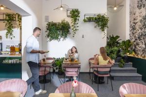 a man walking through a restaurant with people sitting at tables at Hotel Botanica by goodnite cz in Brno