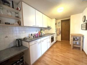 a kitchen with white cabinets and a wooden floor at Sam's Lakeview apartment in Ringgenberg