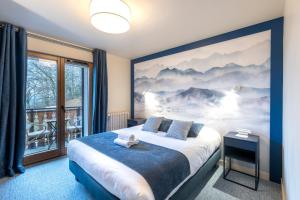 a bedroom with a bed with a large painting on the wall at Hôtel Restaurant Le Bois Joli et SPA in Bernex +80 photos