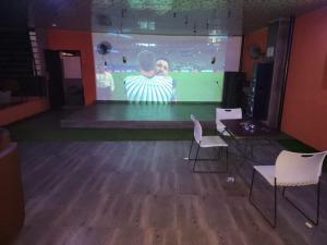 a room with a screen with a man on a stage at Zim Zam View Hotel in Onitsha
