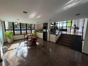 a living room with a table and chairs and windows at Brisamar Suite Hotel in Florianópolis