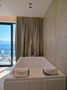 a large bath tub in a room with a balcony at Blue Waves Hotel & Suites in Sarandë