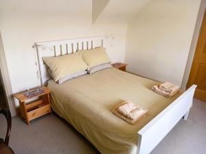a bedroom with a large bed with two towels on it at Ardross Cottage in Aberfoyle