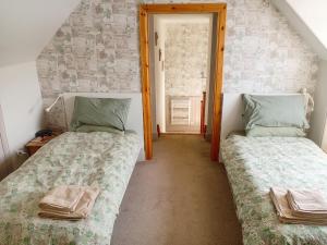 two twin beds in a room with a door at Ardross Cottage in Aberfoyle