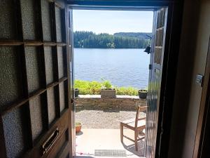 an open door to a view of a lake at Ardross Cottage in Aberfoyle