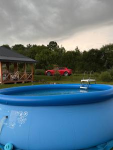 a blue pool with a red car in the background at Aframe in Skhidnitsa
