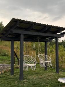 a swing set with two chairs in a gazebo at Aframe in Skhidnitsa