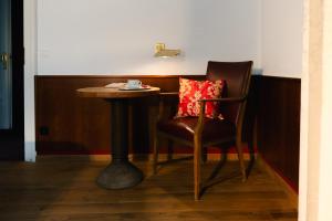 a chair with a pillow sitting next to a table at Villa Widder - Boutiquehotel in Staatsbad Brückenau
