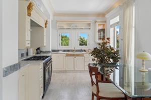 a kitchen with white cabinets and a glass table at Villa Cypress with Private Pool and Mountain Views in Andros