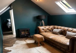 a living room with a leather couch and a stove at Plgs and Blankets in Pucklechurch