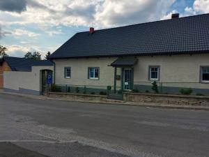 a white house with a black roof on a street at Ferienhaus Strohmayer in Schweiggers