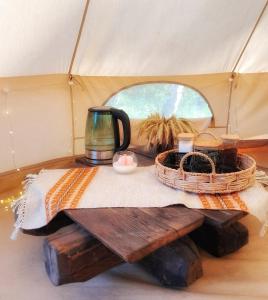a table with a tea pot and baskets in a tent at Glempings Pasaka un pirts I tent and sauna in Vecumnieki