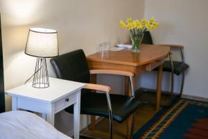 a desk with a chair and a table with a vase of flowers at V8-Kelemen Panzió in Makó
