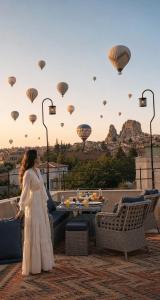 a woman in a white dress looking at hot air balloons at Üçhisar Palace İn Cappadocia in Uçhisar +158 photos
