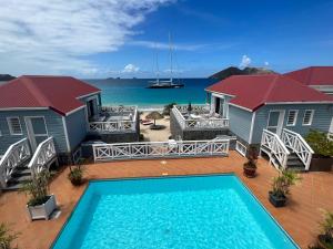 a house with a swimming pool in front of the ocean at Hôtel Baie des Anges in Gustavia
