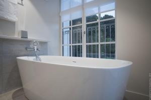 a white bath tub in a bathroom with a window at Grand Slam in Le Vaudreuil