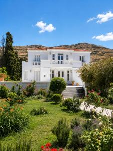 a white house with a garden in front of it at Villa Cypress with Private Pool and Mountain Views in Andros