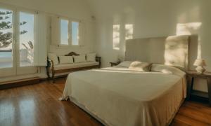 a bedroom with a bed and a couch and windows at Damma Villa in Kamari