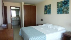 um quarto com uma cama branca e uma casa de banho em Vila das Lagoas - Herdade dos Salgados em Albufeira