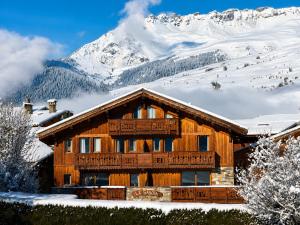a log cabin in the snow with a mountain at Les Dolomites in La Plagne Tarentaise