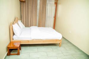 a bed with white sheets and a table in a room at Royce's Apartment in Kigali