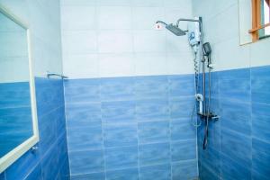 a shower in a bathroom with blue and white tiles at Royce's Apartment in Kigali