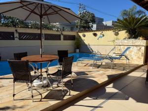 a patio with a table and chairs and an umbrella at casa 300 mts da praia in Juquei
