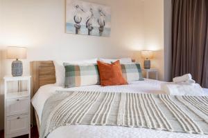 a bedroom with a white bed with pillows and two lamps at Family Friendly, Stylish Floreat, Pool in Perth