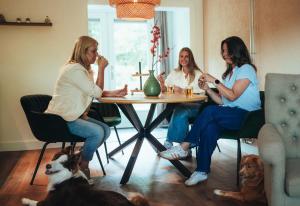three women sitting at a table with a dog at Natuurhuisje 'n Snuffelstee in Markelo