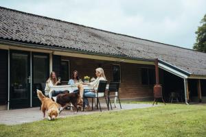 three women sitting at a table with a dog at Natuurhuisje 'n Snuffelstee in Markelo