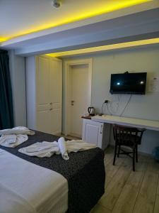 a hotel room with a bed and a desk and a television at Ada Marin Hotel in Urla