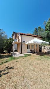 a white house with a patio and an umbrella at Coco free parking in Pržno
